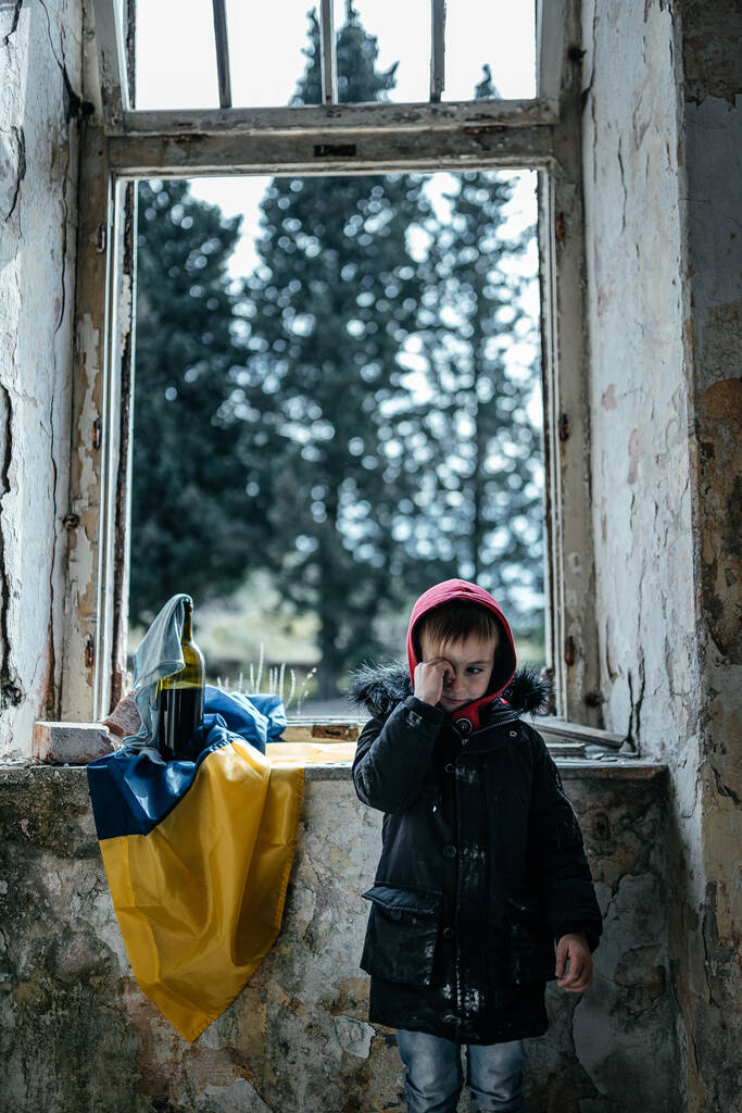 Mały chłopiec w zrujnowanym domu wojny na Ukrainie ukraińskiej flagi - Zdjęcie, obraz