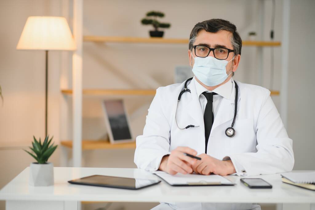 врач-мужчина в медицинской маске и стетоскоп в клинике. - Фото, изображение