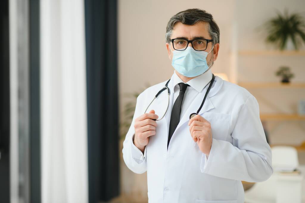 Starší starý zdravotnický lékař v bílém plášti, stetoskopu, brýlích a masce obličeje. Zdravotnický personál koncepce ochrany zdraví. Portrét - Fotografie, Obrázek