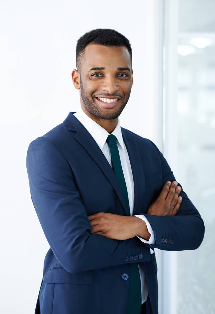 Με αυτοπεποίθηση εταιρική γοητεία. Ένας όμορφος νεαρός Αφροαμερικάνος επιχειρηματίας στέκεται μέσα με τα χέρια του διπλωμένα.. - Φωτογραφία, εικόνα