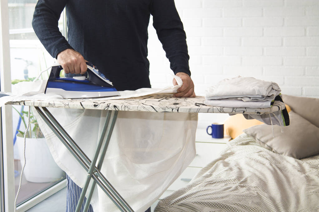 uomo stiratura a casa con il ferro, concetto di uguaglianza nei lavori domestici - Foto, immagini