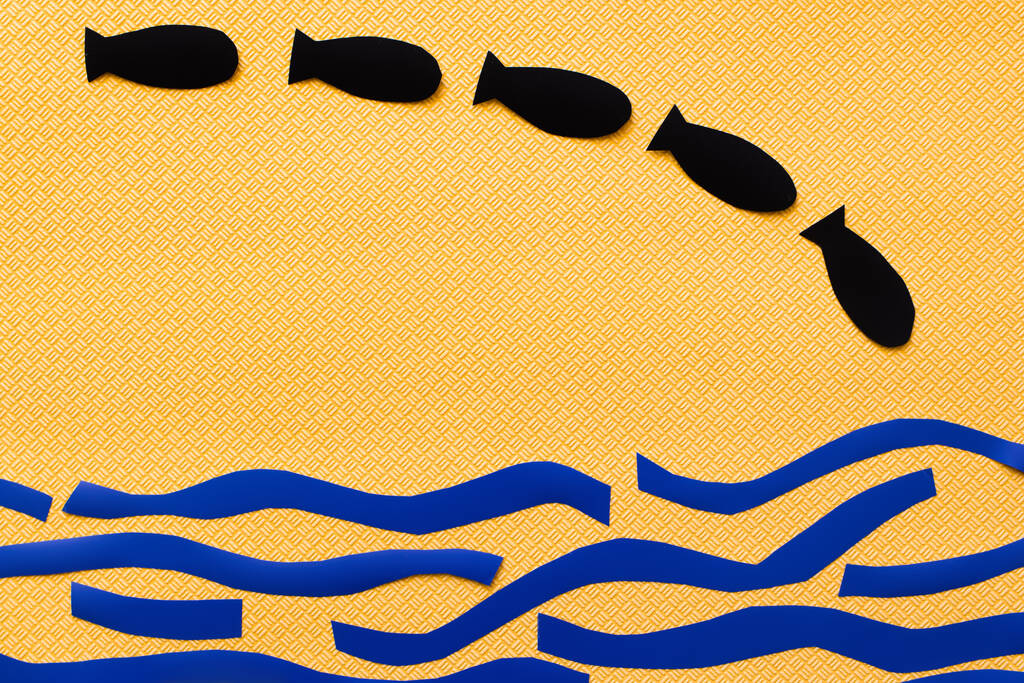 Horní pohled na papírové bomby nad abstraktní lepenkové moře na texturovaném žlutém pozadí  - Fotografie, Obrázek