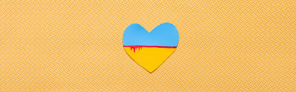 Draufsicht der ukrainischen Flagge mit Blut in Herzform auf strukturiertem gelben Hintergrund, Banner  - Foto, Bild