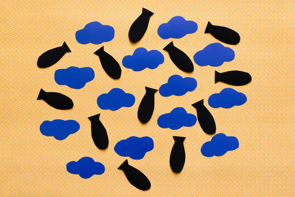Vue du dessus des nuages en carton bleu et des bombes en papier sur fond jaune texturé  - Photo, image