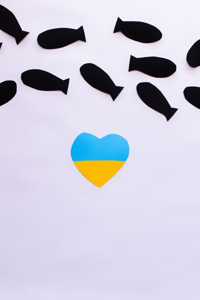 Vista superior da bandeira ucraniana em forma de coração sob bombas de papel sobre fundo branco  - Foto, Imagem