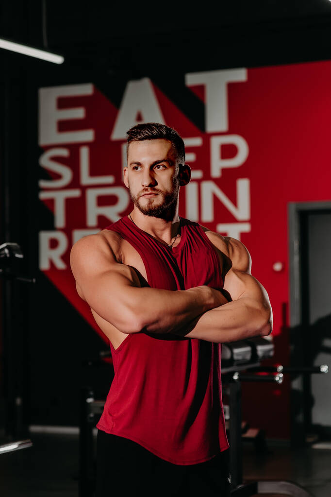 Retrato de um homem muscular em calções e camiseta vermelha posando
 - Foto, Imagem