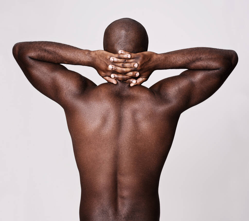 Vissza az izomalapokhoz. Visszapillantás egy izmos afro-amerikai férfiról, aki a nyaka mögött tartja a kezét.. - Fotó, kép