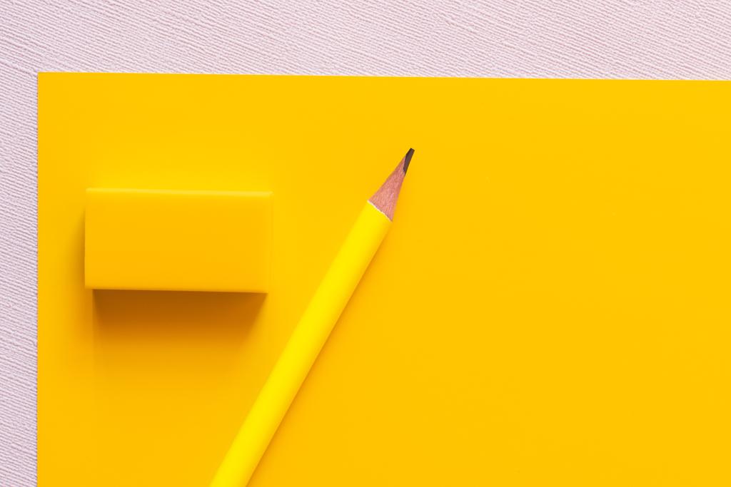vista dall'alto della matita vicino gomma su giallo e bianco - Foto, immagini