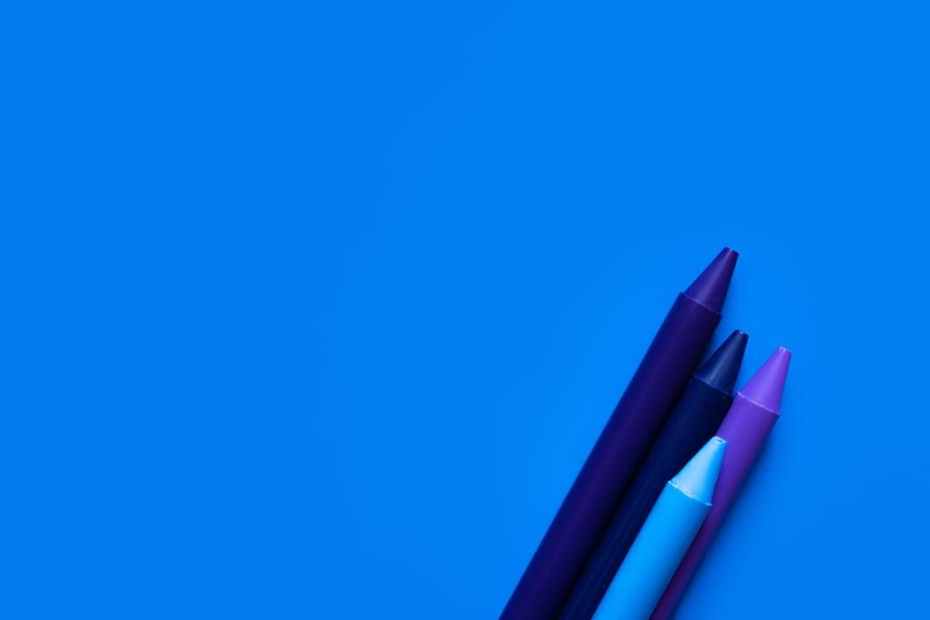 κορυφαία άποψη των κραγιόνων βαθμίδωσης σε φωτεινό μπλε φόντο - Φωτογραφία, εικόνα