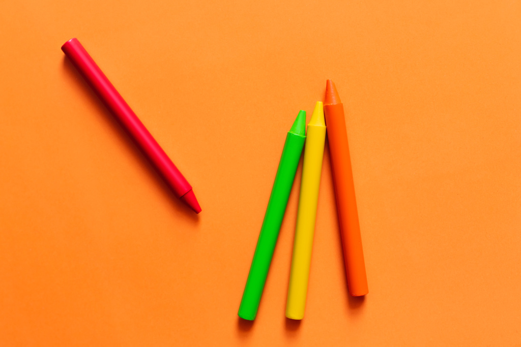 Draufsicht auf Set mit bunten Buntstiften auf orangefarbenem Hintergrund - Foto, Bild