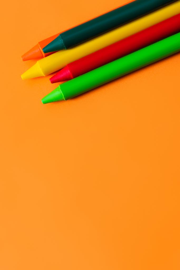 πάνω όψη του συνόλου με πολύχρωμα κηρομπογιές σε πορτοκαλί φόντο - Φωτογραφία, εικόνα