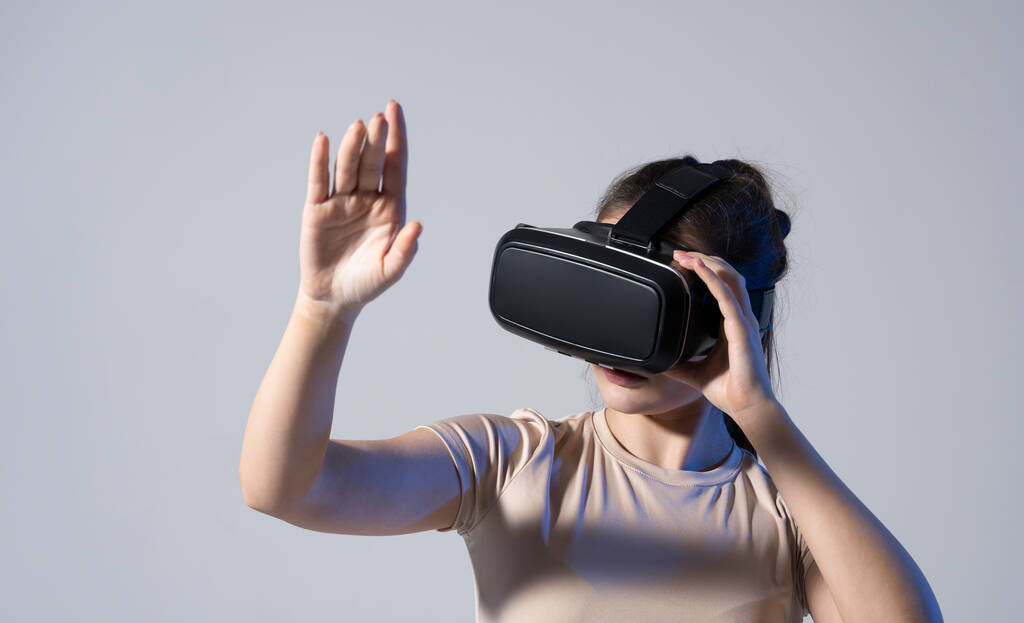 Gros plan de la jeune femme debout en studio portant des lunettes VR et faisant glisser les mains en l'air. Technologie de réalité virtuelle. - Photo, image