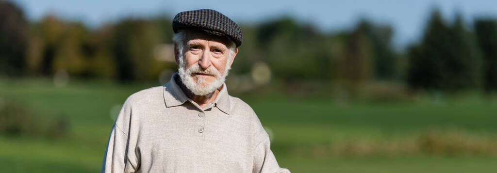 starszy mężczyzna w płaskiej czapce patrząc w kamerę, baner - Zdjęcie, obraz