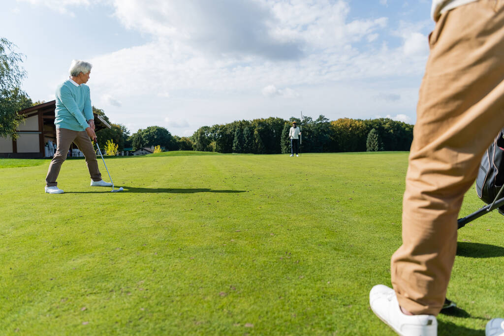 senior asian man playing golf with wealthy interracial friends on lawn - Фото, изображение
