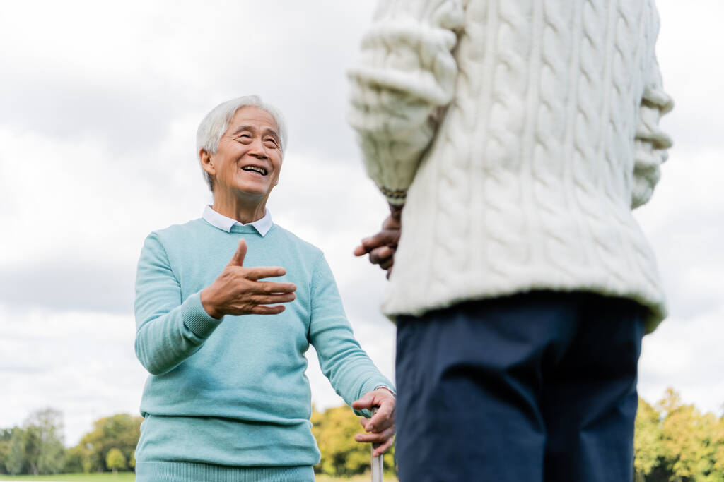Niedrigwinkel-Ansicht von glücklichen Senior asiatischen Mann im Gespräch mit afrikanisch-amerikanischen Freund - Foto, Bild