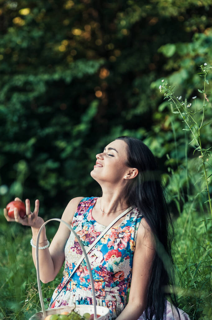 Egy lány egy pikniken az erdőben. Egy gyönyörű nő gyümölcsöt eszik.. - Fotó, kép