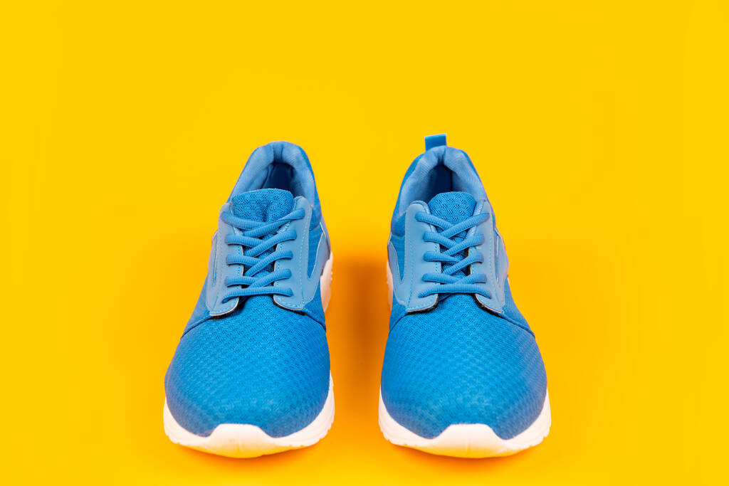 paio di comode scarpe sportive blu su sfondo giallo, abbigliamento sportivo - Foto, immagini