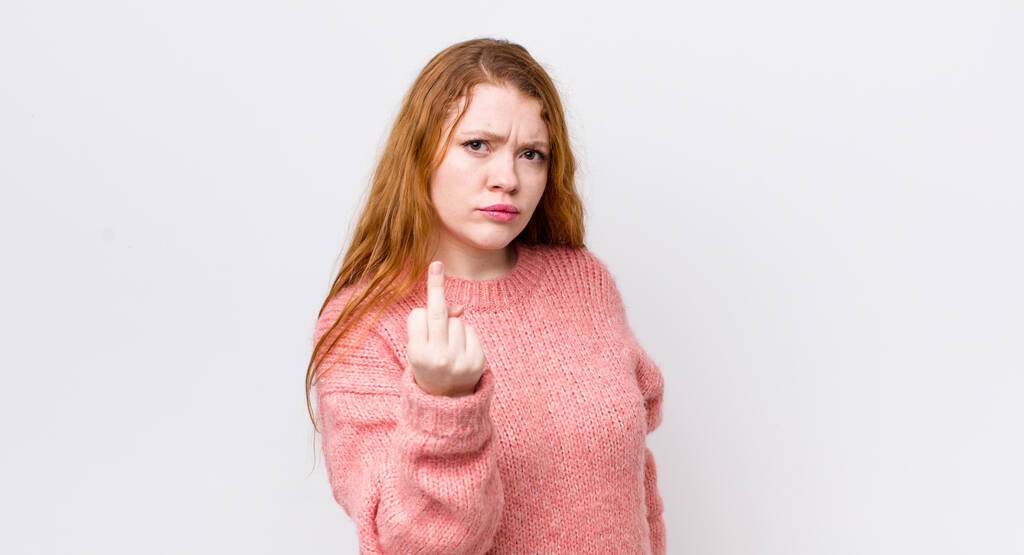 bonita mujer cabeza roja sintiéndose enojado, molesto, rebelde y agresivo, volteando el dedo medio, luchando - Foto, Imagen