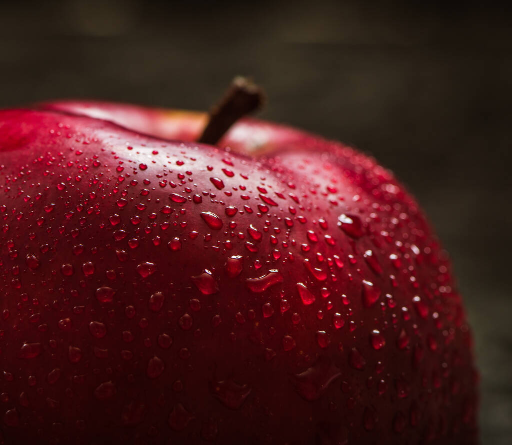 Красное яблоко закрывается. Красное яблоко на черном фактурном фоне. Яблоки с каплями воды. текстовое пространство Здоровое питание для вегетарианцев. - Фото, изображение