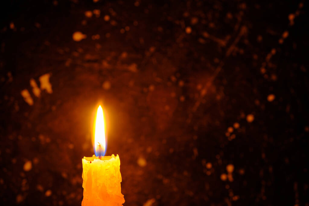 Свеча ярко пылает у темной стены - Фото, изображение