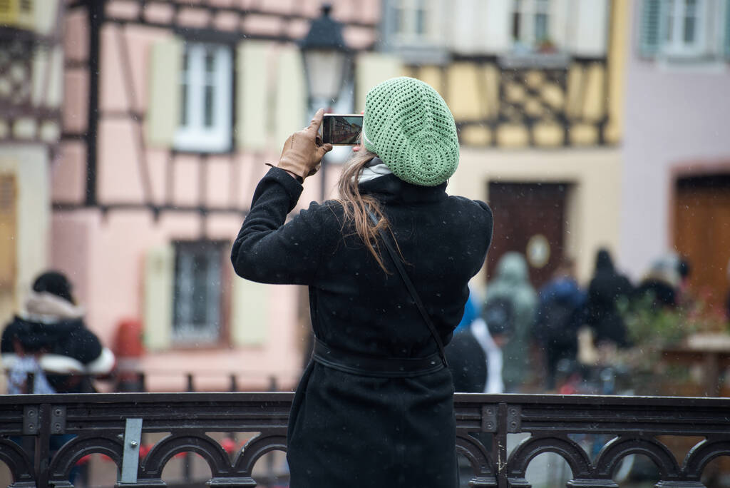 Portret op achteraanzicht van een toerist die een foto maakt met haar smartphone in Colmar Frankrijk - Foto, afbeelding