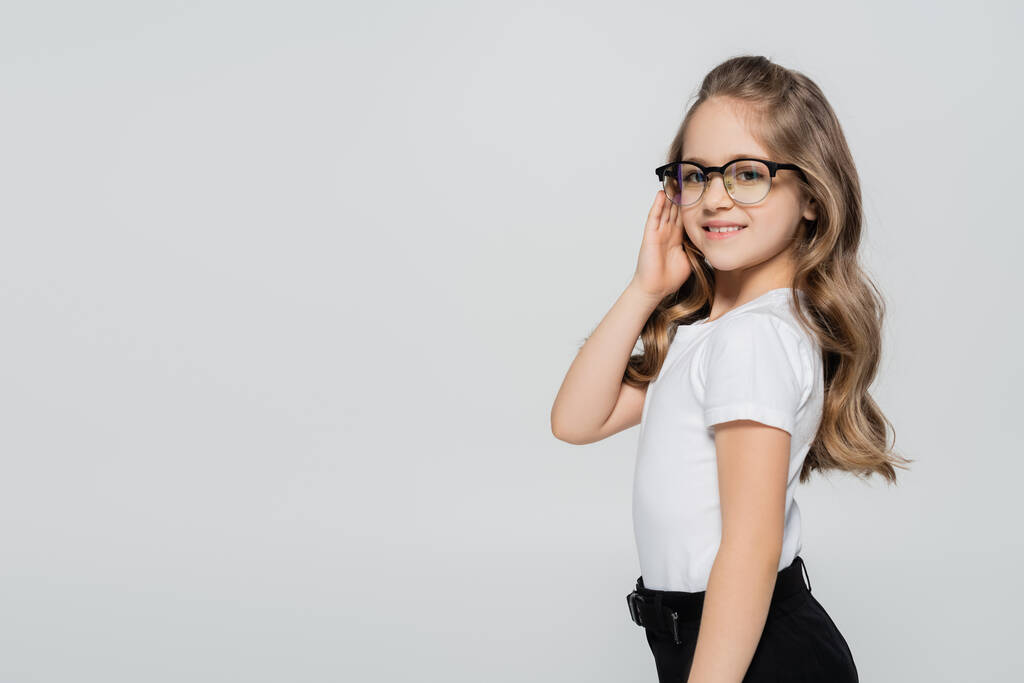 hymyilevä tyttö valkoinen t-paita säätämällä silmälasit eristetty harmaa - Valokuva, kuva
