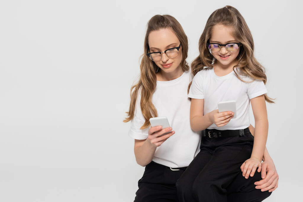 woman and child in eyeglasses using smartphones isolated on grey - Photo, Image