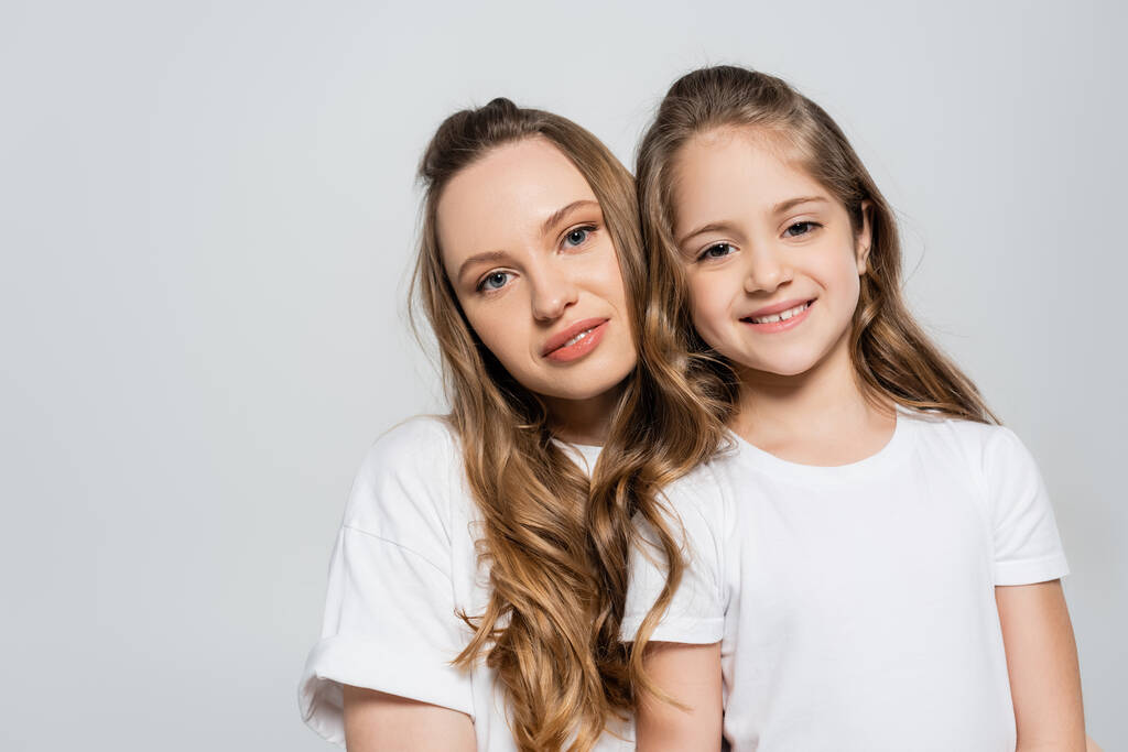 mother and daughter with long hair looking at camera isolated on grey - Photo, Image