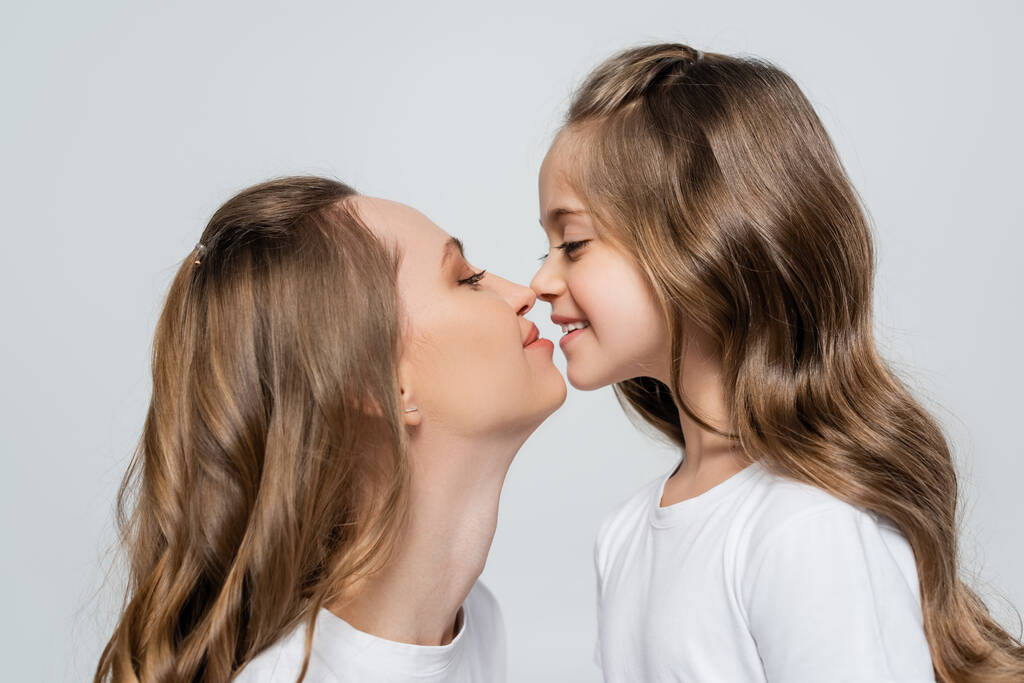 side view of woman and daughter with long hair looking at each other face to face isolated on grey - Photo, Image