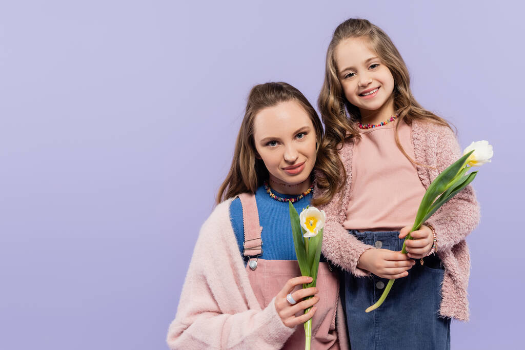 madre e hija complacidas sosteniendo tulipanes aislados en púrpura  - Foto, Imagen