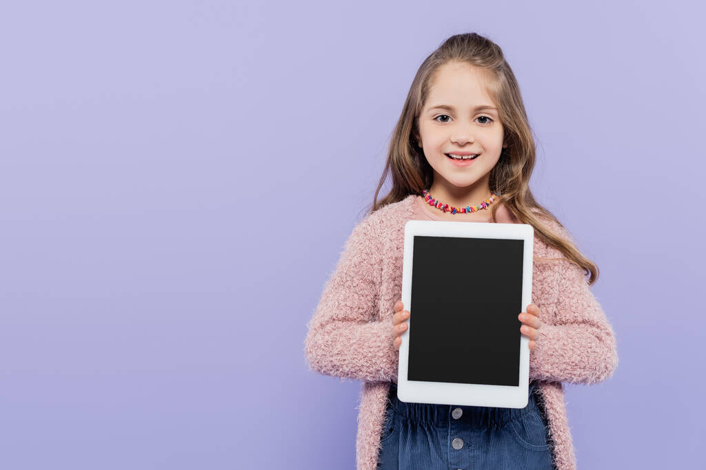 boldog lány gazdaság digitális tabletta üres képernyő elszigetelt lila - Fotó, kép