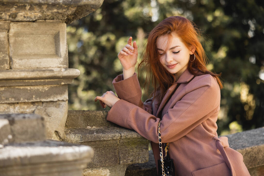 young happy redhead woman in coat posing outside  - Photo, Image