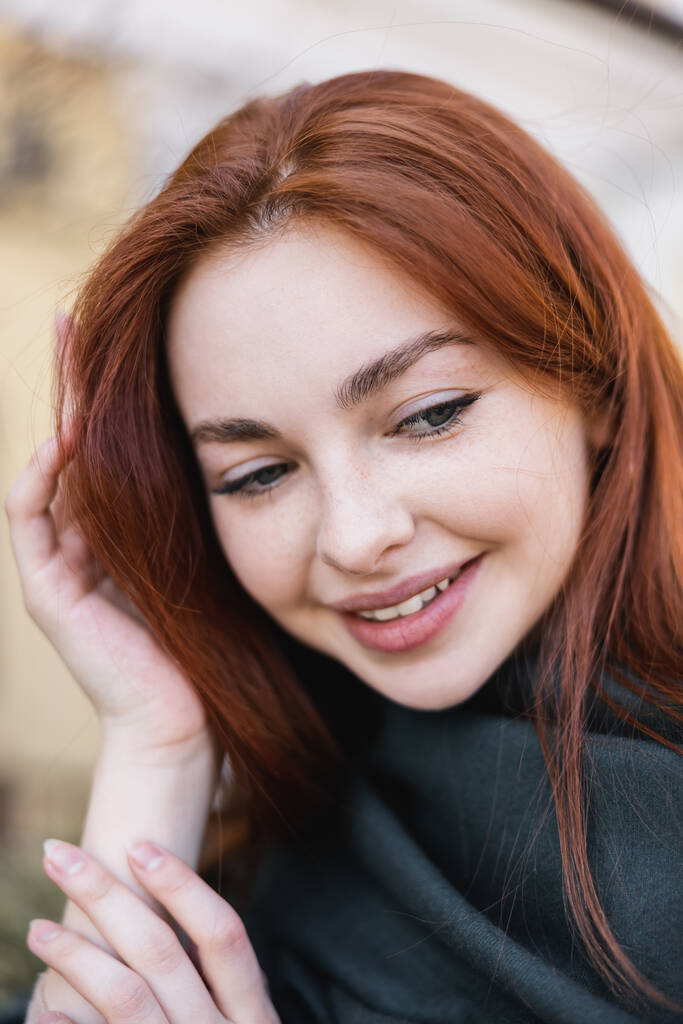 portrait of young redhead woman in headscarf smiling while looking down - Photo, Image