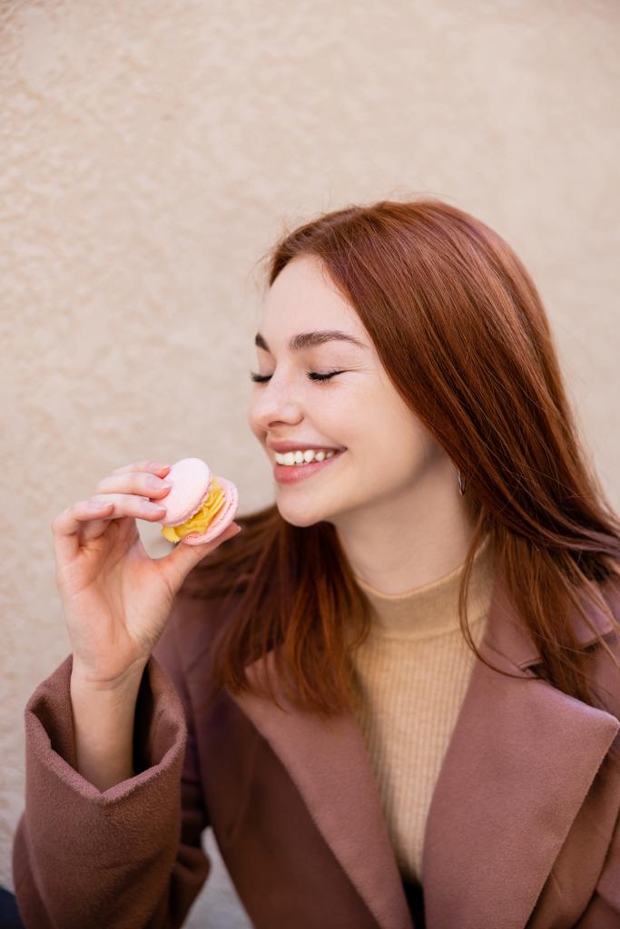 šťastná mladá žena s zrzavými vlasy drží sladké macaron - Fotografie, Obrázek
