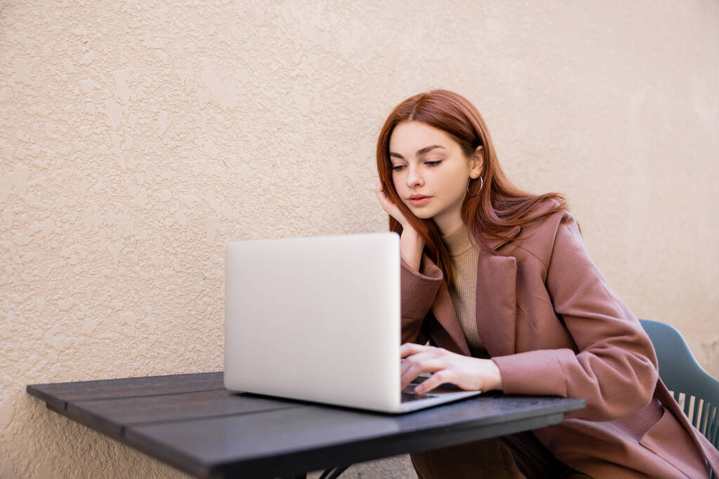 giovane donna con i capelli rossi utilizzando il computer portatile al di fuori - Foto, immagini