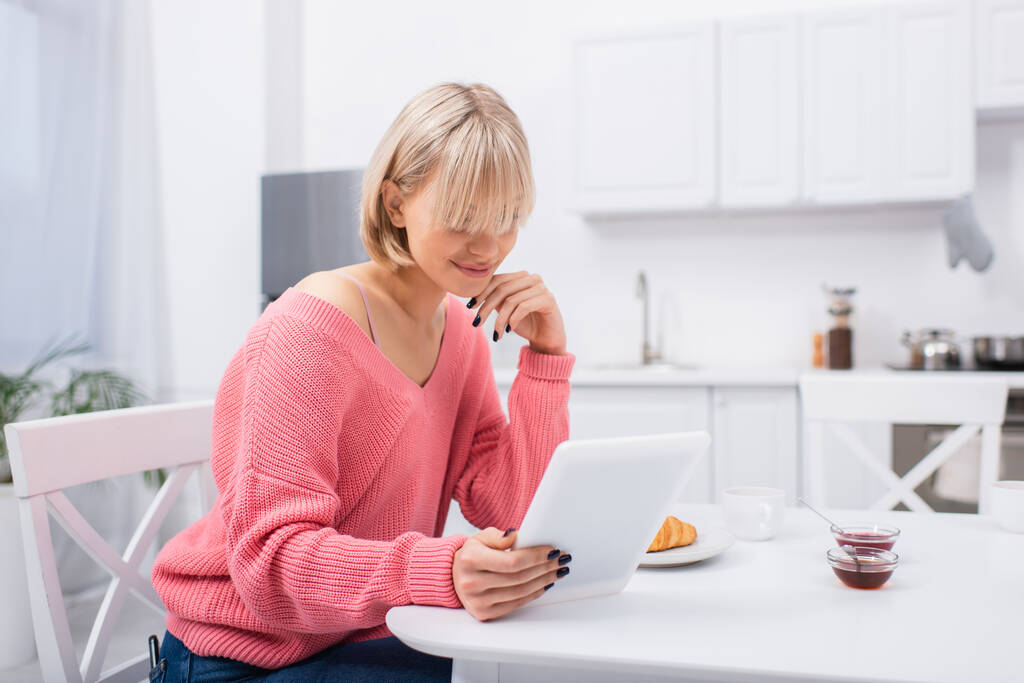 allegra donna bionda utilizzando tablet digitale durante la colazione  - Foto, immagini