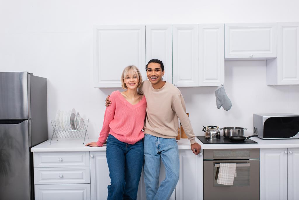 ευτυχισμένο πολυεθνικό ζευγάρι στέκεται στη σύγχρονη κουζίνα  - Φωτογραφία, εικόνα