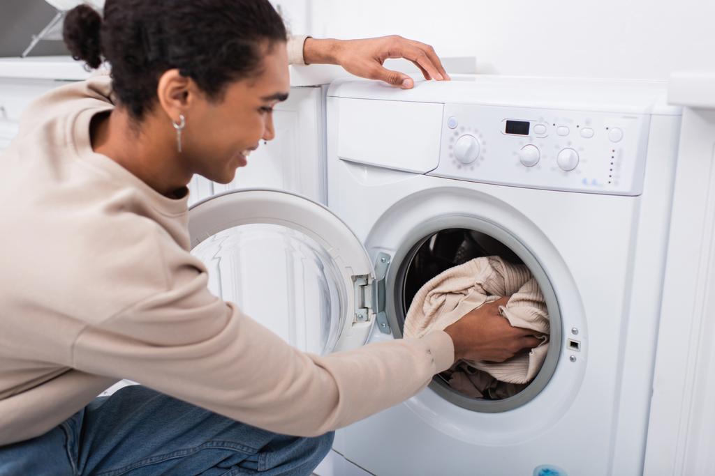 boldog afro-amerikai férfi tesz mosoda a mosógép - Fotó, kép