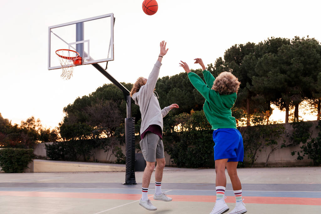 δύο νεαροί φίλοι που παίζουν μπάσκετ σε γήπεδο της πόλης, έννοια του αστικού αθλητισμού στο δρόμο, αντιγραφή χώρου για κείμενο - Φωτογραφία, εικόνα