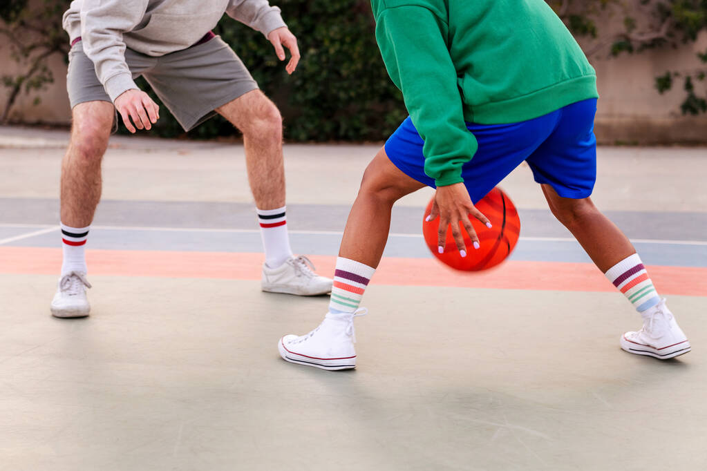 nogi dwóch nierozpoznanych przyjaciół grających w koszykówkę na dworze miejskim, koncepcja sportów miejskich na ulicy - Zdjęcie, obraz