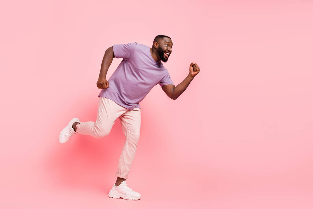 Photo of attractive charming guy dressed violet t-shirt running fast empty space isolated pink color background - Photo, Image
