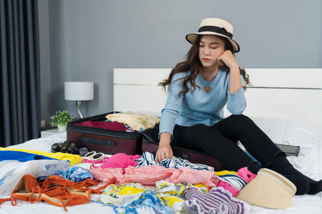 gestresste vrouw problemen met het inpakken van een koffer op een bed thuis, vakantie reisconcept - Foto, afbeelding
