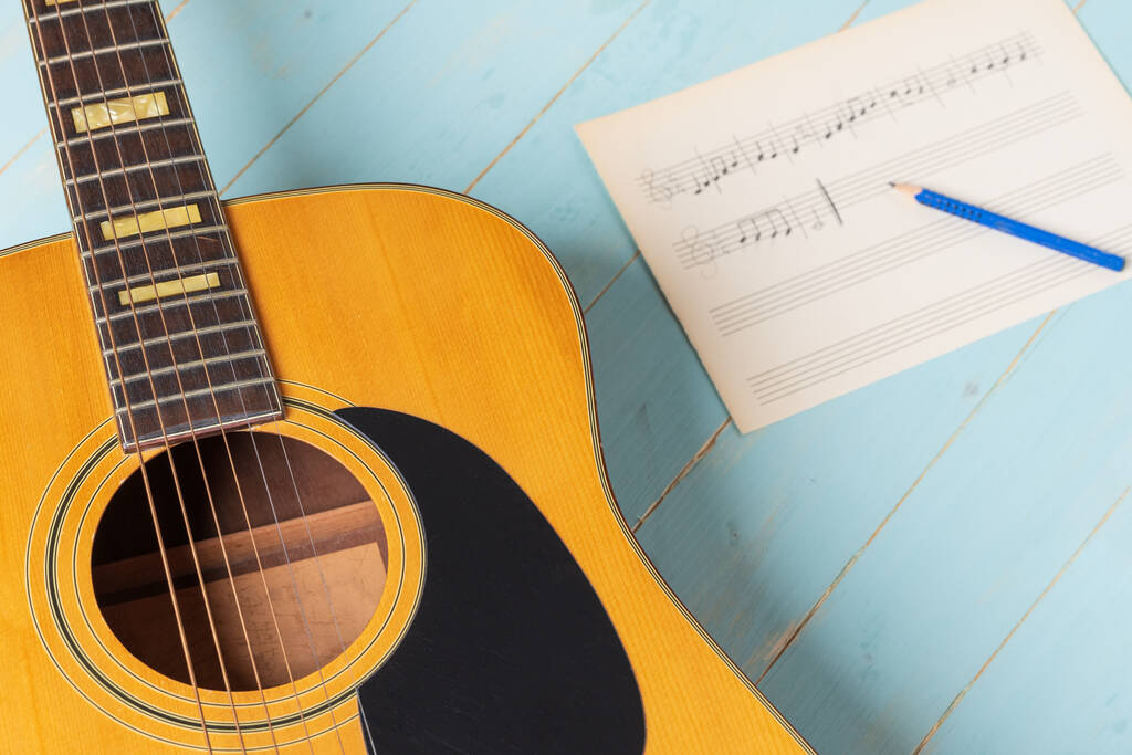 Scène d'enregistrement musicale avec guitare, partition et crayon sur table en bois, gros plan - Photo, image