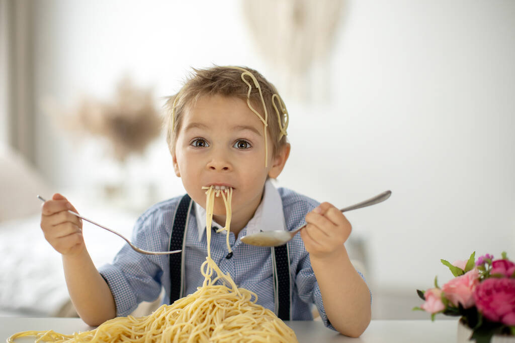 Söpö esikoululainen, vaalea poika, spagettia syömässä kotona, sotkemassa paikkoja, hauskoja hetkiä - Valokuva, kuva