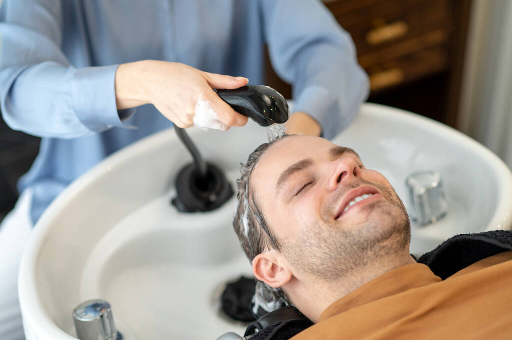 Coiffeur laver les cheveux au client masculin dans un salon de beauté - Photo, image