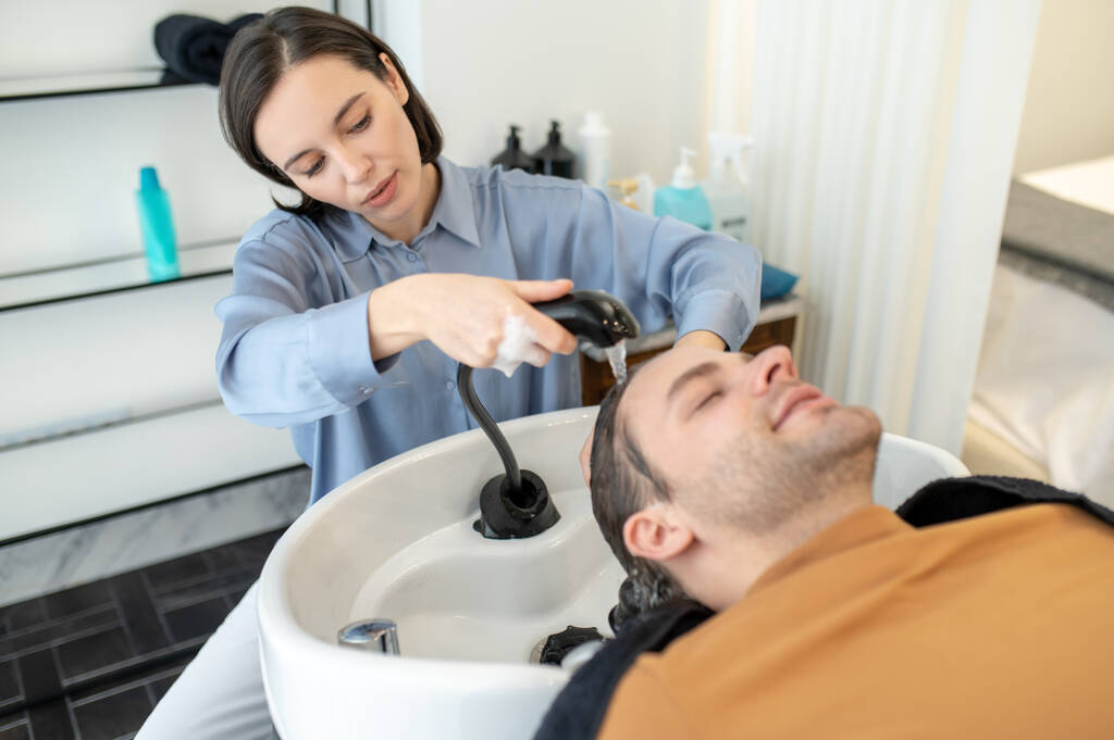 Kuaför bir güzellik salonunda erkek müşteriye saç yıkıyor. - Fotoğraf, Görsel