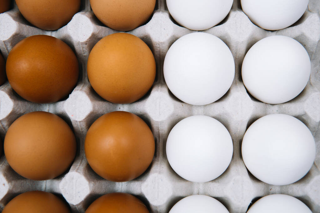 Flache weiße und braune Eier in Eipapierschachtel legen. Frische Hühnereier im Hintergrund. Natürliches Bio-Ei von oben. Gesunde, echte Nahrung - Foto, Bild
