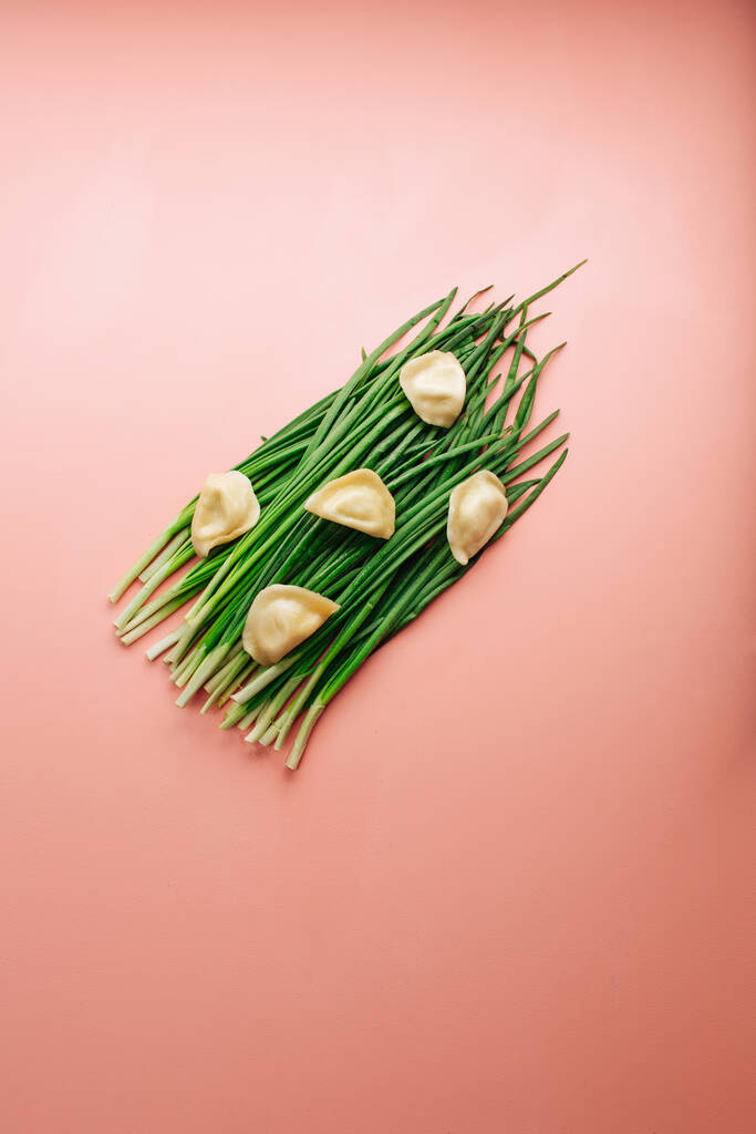 green fresh chives on a pink background. dumpling laid out on top. High quality photo - Photo, Image