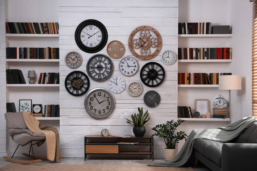 Intérieur élégant avec table console, mobilier confortable et collection d'horloges différentes sur mur blanc - Photo, image