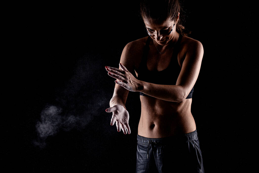Kickboxer kirl met magnesiumpoeder op haar handen stompend met zichtbaar stof. - Foto, afbeelding